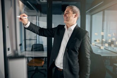 Ofisteki beyaz tahtada yazan neşeli iş adamı.