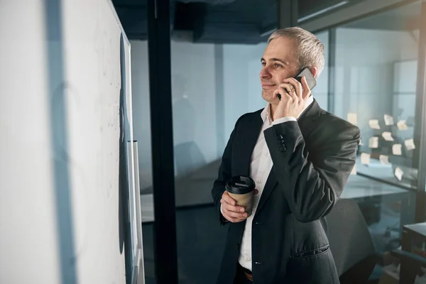 İş yerinde cep telefonuyla konuşan neşeli erkek girişimci. — Stok fotoğraf