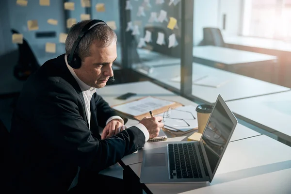Intelligent man i hörlurar med bärbar dator på kontoret — Stockfoto