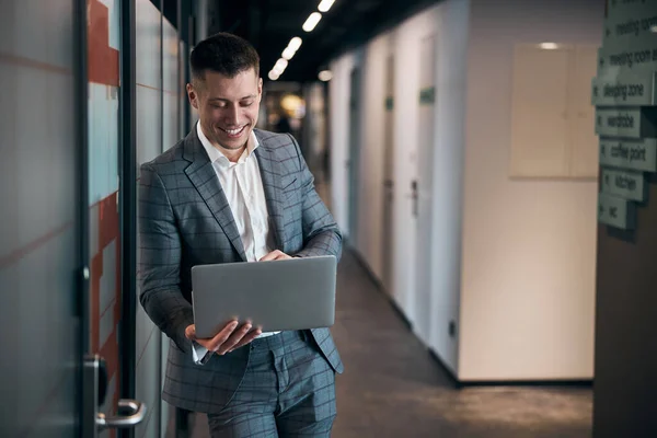 Fröhlicher junger Mann benutzt Notizbuch im Büroflur — Stockfoto