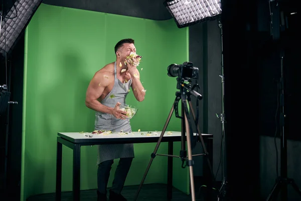 Muscular fome homem gravação de vídeo e comer salada no estúdio — Fotografia de Stock