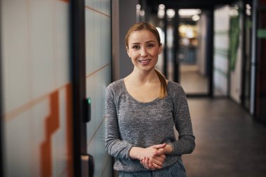 Ofis koridorunda gülümseyen bir çalışan.