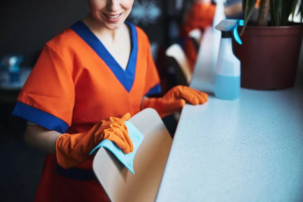 Merry woman cleaning a furniture item with a wet absorbent cloth — Stock Photo, Image