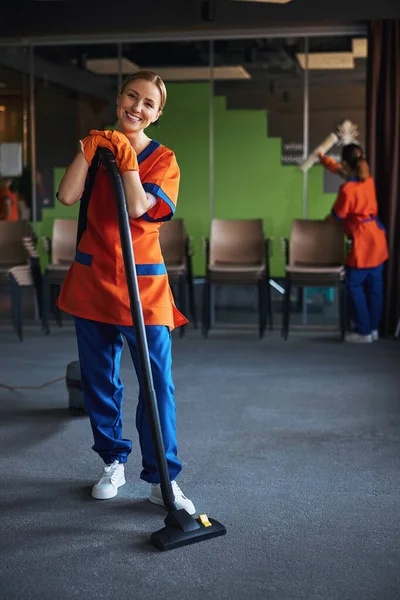 Sonriente señora de la limpieza posando para la cámara durante la limpieza — Foto de Stock