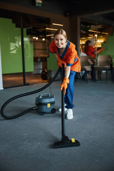 Sonriendo bonita señora de la limpieza aspirando el suelo — Foto de Stock