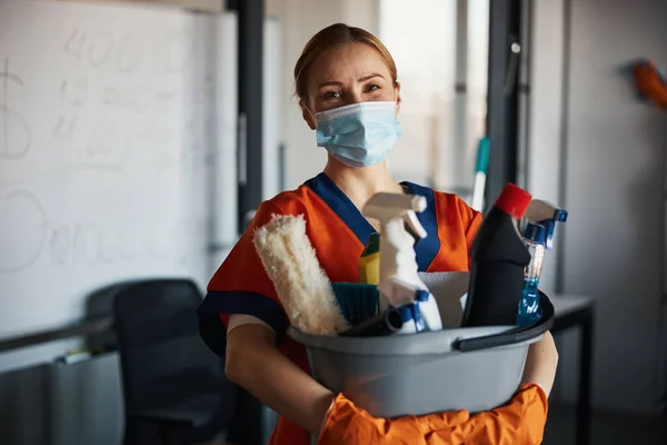 Limpiador en una mascarilla que muestra sus productos de limpieza — Foto de Stock