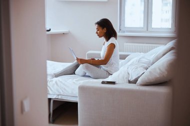 Yatak odasında defter kullanan hoş bir genç kadın.