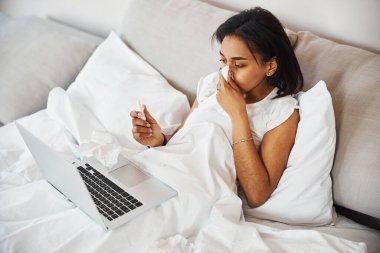 Grip olmuş genç bir kadın evde doktorla görüşüyor.