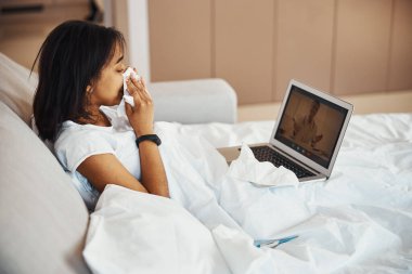 Grip olmuş genç bir kadın evde doktorla konuşuyor.