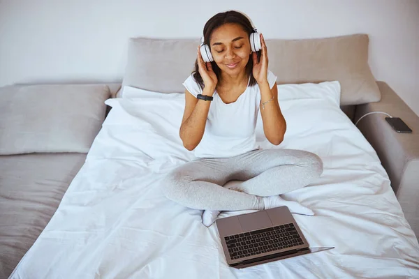 Donna affascinante ascoltare musica e utilizzare il computer portatile a casa — Foto Stock