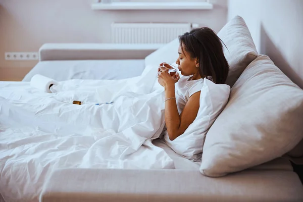 Charmante jonge vrouw met griep thee drinken thuis — Stockfoto