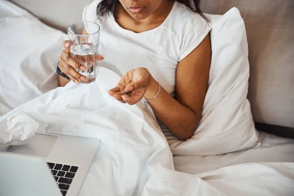 Malata giovane donna in possesso di pillola e bicchiere d'acqua — Foto Stock