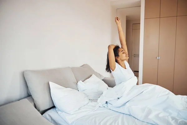 Mooie jonge vrouw wakker en stretching in de ochtend — Stockfoto