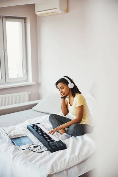 Όμορφη νεαρή γυναίκα παίζει synthesizer και χρησιμοποιώντας φορητό υπολογιστή — Φωτογραφία Αρχείου