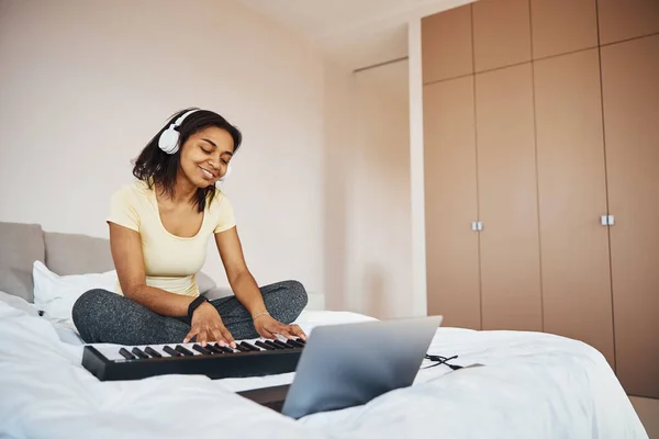 Γοητευτική νεαρή γυναίκα με ακουστικά παίζει synthesizer στο σπίτι — Φωτογραφία Αρχείου