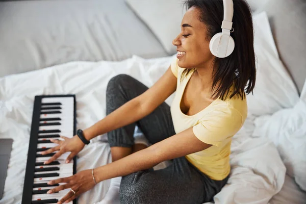 Allegro musicista femminile che suona sintetizzatore a casa — Foto Stock