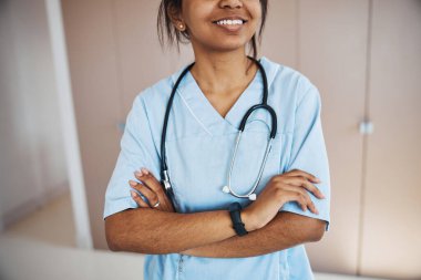 Steteskoplu neşeli bayan doktor klinikte duruyor.