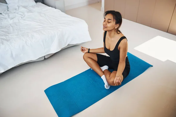 Affascinante giovane donna che pratica yoga a casa — Foto Stock