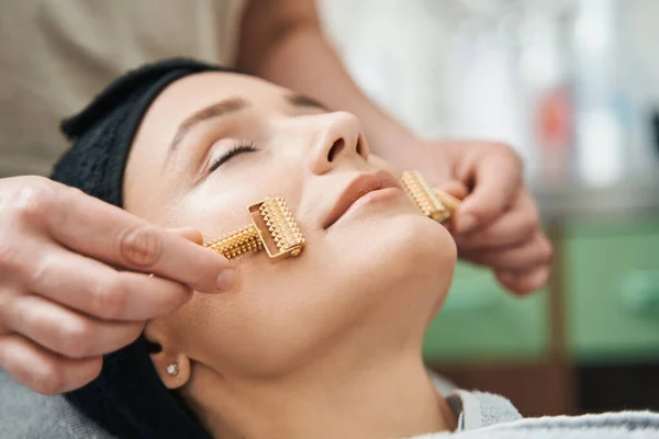 Cosmetici masseren het gezicht van de klant met acupressuur metalen roller masseerders — Stockfoto