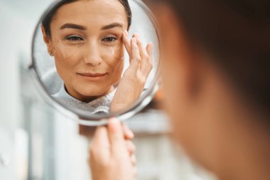 Yüzüne dokunan gözlüklü bir spa müşterisi.