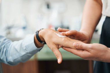 Kadın eline kozmetik ürün uygulayan nitelikli bir güzellik uzmanı.