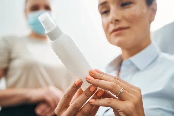 Cliente femenino enfocado viendo un producto cosmético en sus manos — Foto de Stock