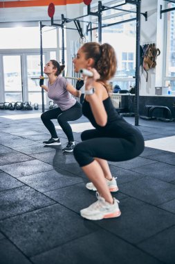 Jimnastik sopalarıyla spor yapan atletik kadınlar.