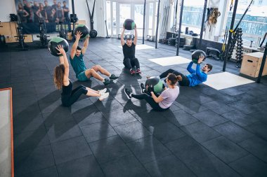 Yerde grup çalışması yapan beş atletik insan.