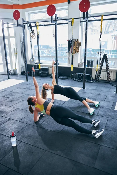 Kvinnlig tränare och hennes klient arbetar sina sneda magmuskler — Stockfoto