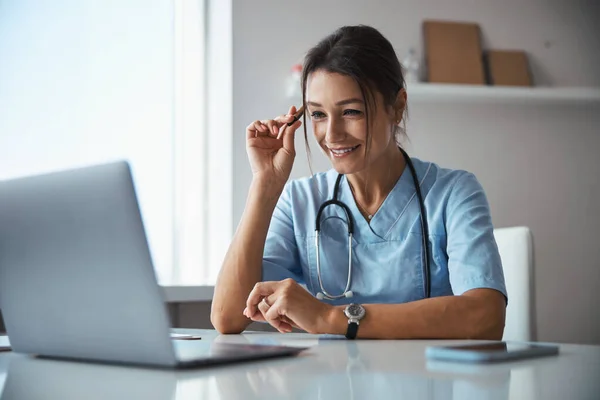 Joyeux médecin féminin en utilisant un ordinateur portable dans la clinique — Photo