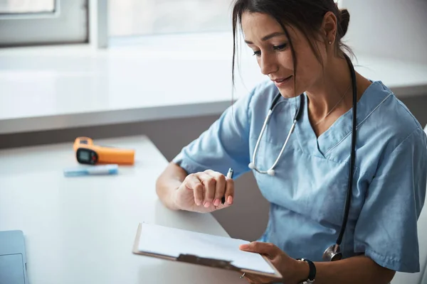 Charmante femme médecin faisant de la paperasse à la clinique — Photo