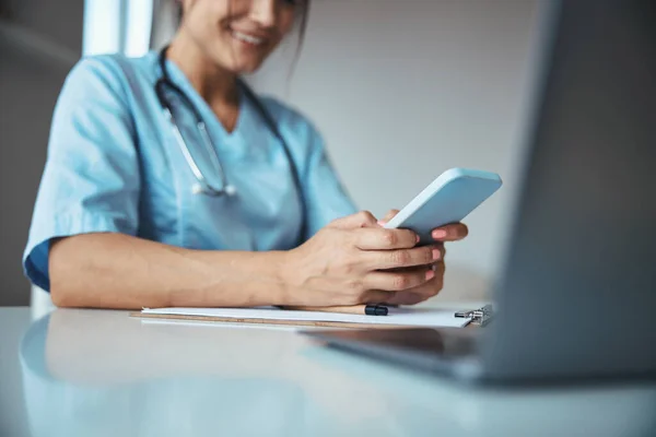 Médecin féminin joyeux utilisant le téléphone portable dans la clinique — Photo