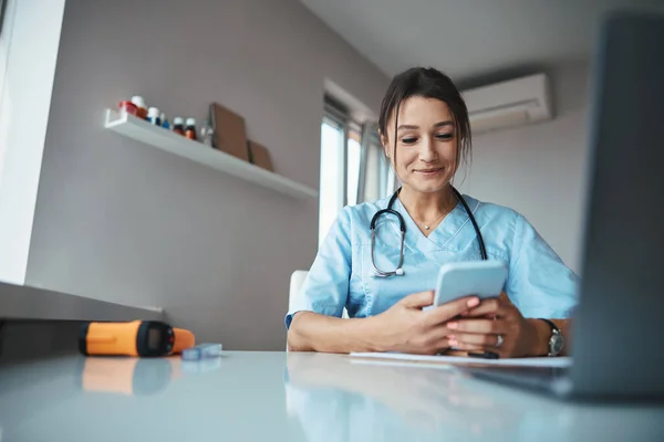 Charmante femme médecin utilisant le téléphone portable en clinique — Photo