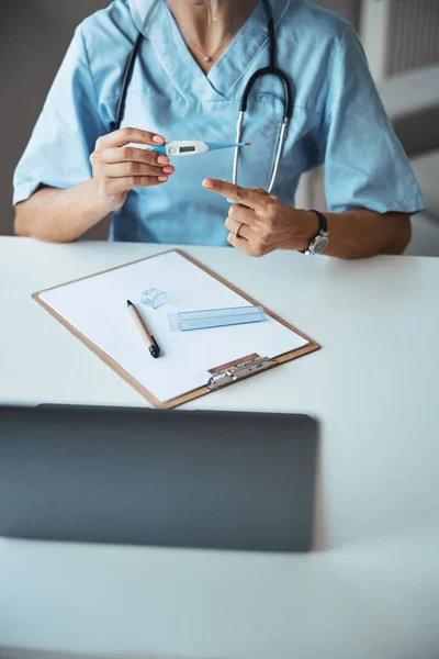 Médecin femelle pointant vers le thermomètre numérique en clinique — Photo