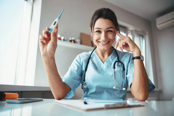 Médecin féminin joyeux avec stéthoscope tenant thermomètre numérique — Photo