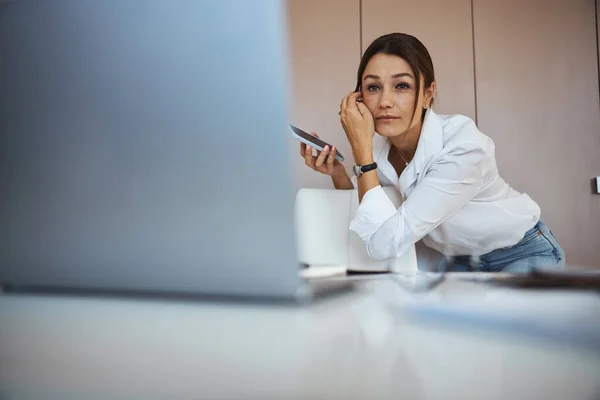 Vacker kvinna som använder mobiltelefon och bärbar dator på jobbet — Stockfoto