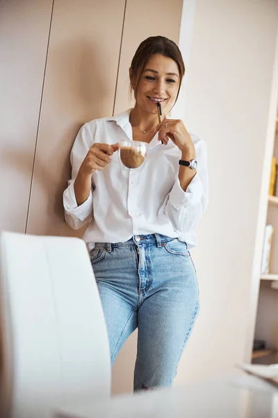 Belle femme joyeuse buvant du latte au travail — Photo