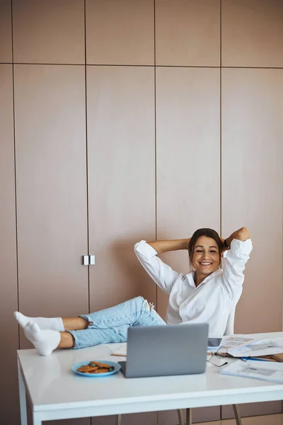 Vrolijke vrouw zit aan tafel met laptop op het werk — Stockfoto