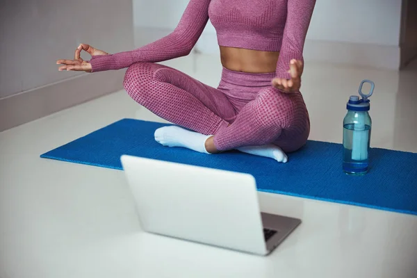 Mulher esportiva praticando ioga e usando notebook em casa — Fotografia de Stock