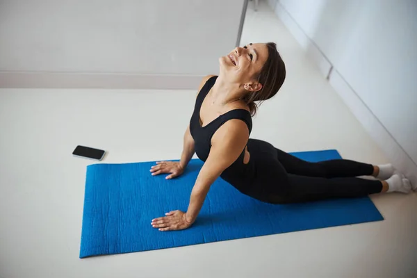 Mulher alegre desportiva praticando ioga em casa — Fotografia de Stock