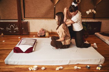 Kadın spa çalışanı Tayland masajı sırasında kadın kolunu çekiyor.