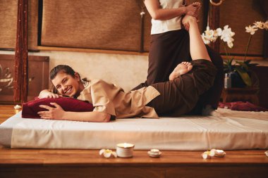 Gülen kadın Tayland uzmanından ayak masajı yaptırıyor.