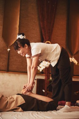 Taylandlı kadın masajcı ayaklarını birbirine sıkıştırıyor.