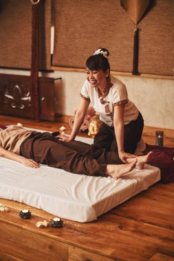 Neşeli bayan masajcı müşteriye sol bacağını bastırıyor.