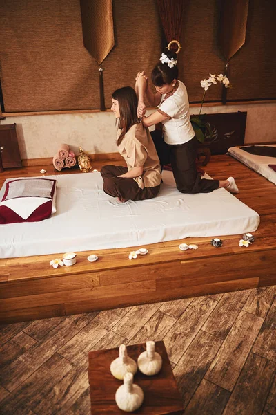 Spa salonu masözü kadınlara kol esnetme hareketi yapıyor.