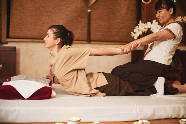 Frau beugt sich mit Hilfe von Thai-Massageexpertin zurück — Stockfoto