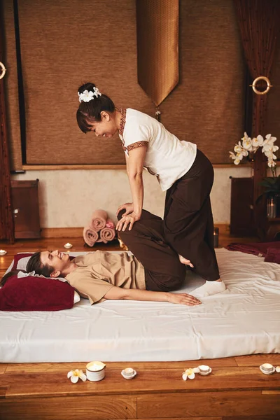 Femmina tirando su ginocchia con Thai massaggiatrice premendo su di loro — Foto Stock