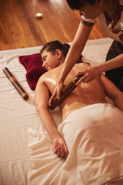 Kadın kaplıca çalışanı kadın tarafına silindir ile masaj yapıyor.