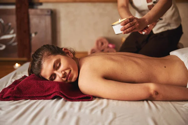 Donna riposante con candela da massaggio girata sulla schiena — Foto Stock