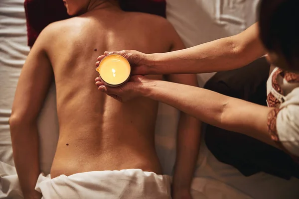 在美容院客人赤身裸体的背面按摩蜡烛 — 图库照片